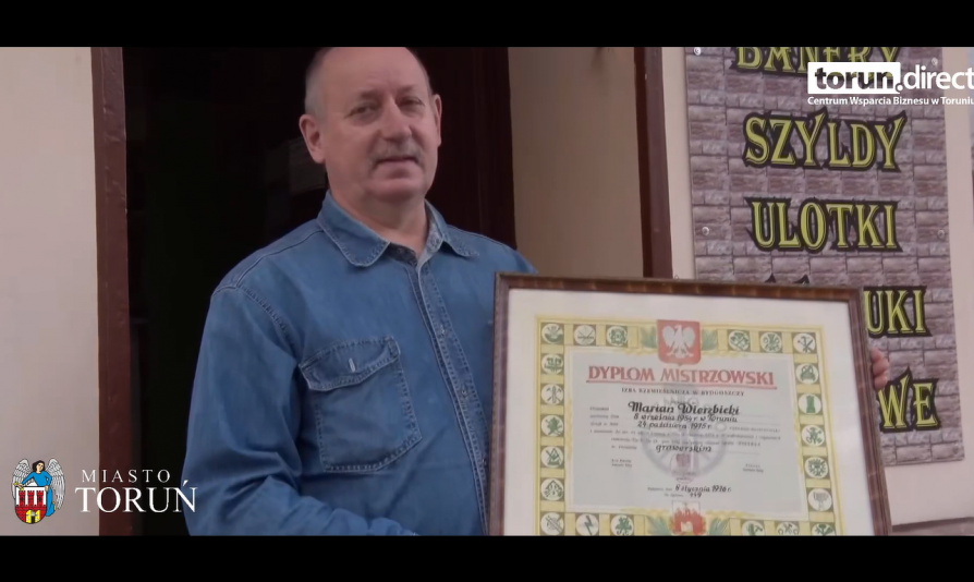 Pan Marian Wierzbicki - właściciel Toruńskiej Wytwórni Stempli - pozujący z dyplomem mistrzowskim przed swoim zakładem przy Placu Rapackiego 5 w Toruniu