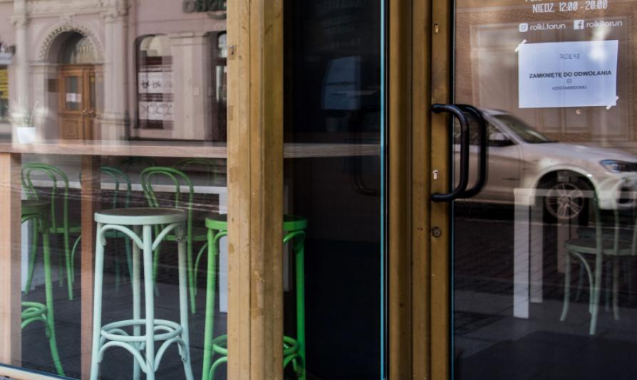 Wejście do lokalu, na drzwiach przywieszona kartka z napisem zamknięte do odwołania #zostań w domu