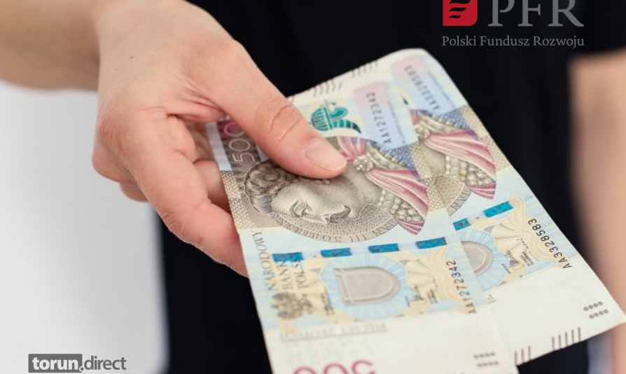 Zdjęcie przedstawia osobę trzymającą dwa banknoty 500 zł  i logotyp PFR